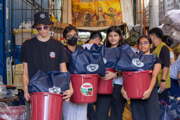 ISM middle school students pose for photos with the relief goods they packed. 【Photo by Marella Saldonido】