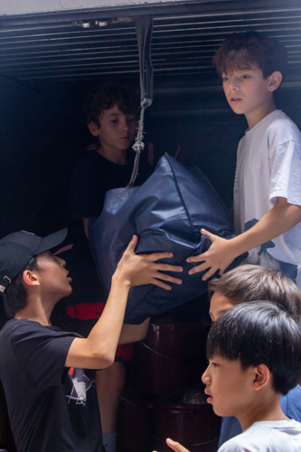 ISM middle school students work together in loading the packed relief goods into the truck. 【Photo by Marella Saldonido】