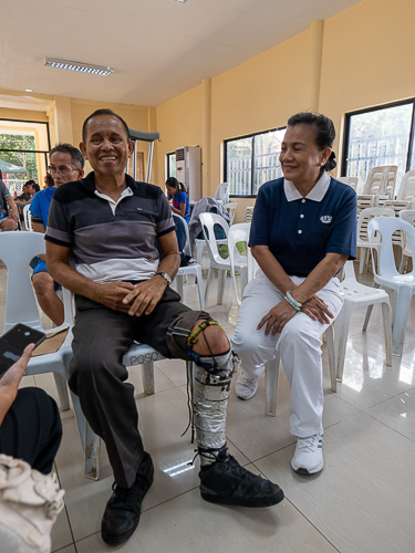 Derby Sebilo (left) shares the story of his self-made prosthesis with Tzu Chi volunteer Jessica Enriquez (right).