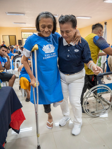 Jessica Enriquez, a Tzu Chi volunteer (right), assists a prosthesis recipient during the fitting process.