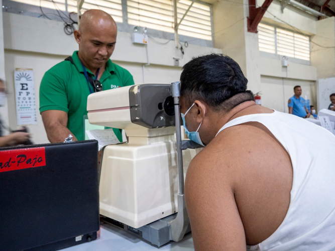 A patient in the ophthalmology area of the medical mission gets his eyes assessed for free reading glasses.