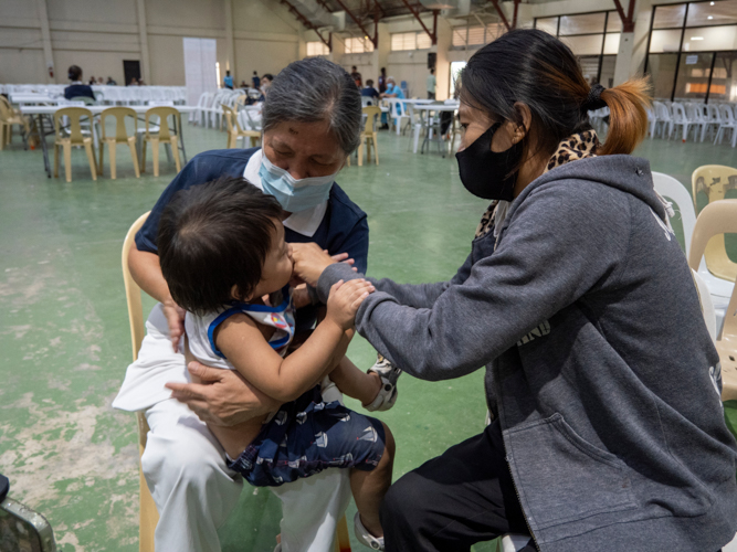 A Tzu Chi volunteer helps a pediatric patient’s mom hold her son.