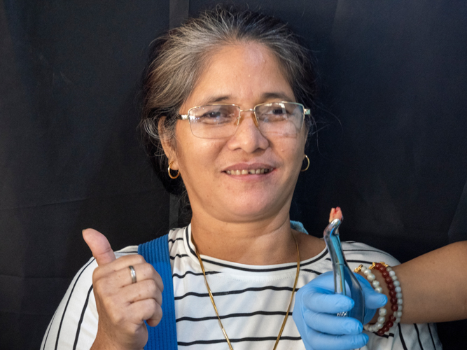 A dental patient happily poses after her tooth extraction.