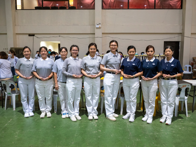 Tzu Chi volunteers helping at the pharmacy area of the medical mission pose together for a photo.