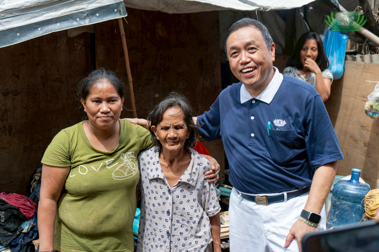 Tzu Chi volunteer Benson Lao (right) comforts the families affected by Typhoon Tino. Here, he heard the story of Lorina Caño (left), who stayed in Talisay to be with her mother (center).