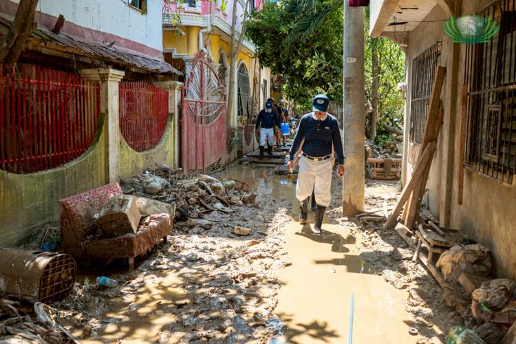 A Tzu Chi volunteer walks through the muddied streets of Galaxy Danglag, Consolacion, Cebu.