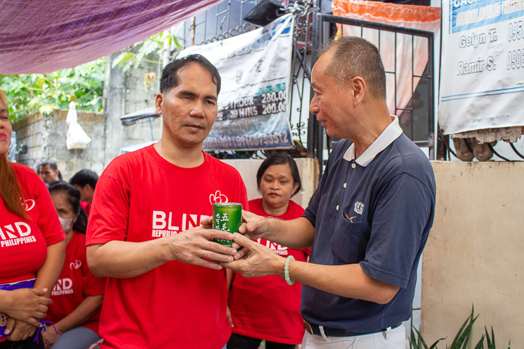 Blind Republic Philippines President Ramir Sayson (left) turns over his coin bank donation to Luis Diamante (right).  【Photo by Marella Saldonido】