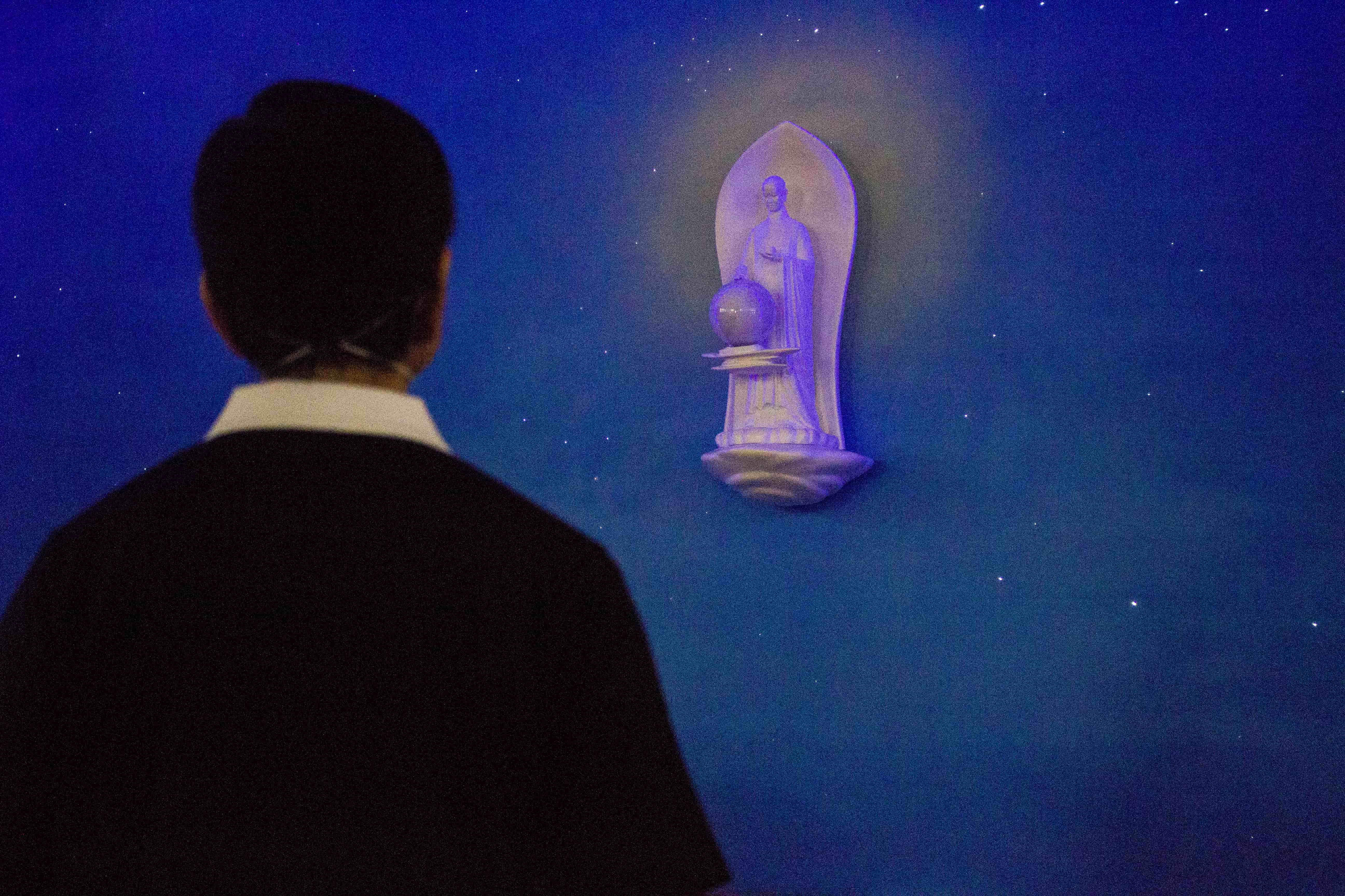 A volunteer admires the statue of Buddha amidst a reproduction of a starry night sky at the Jing Si Hall. 【Photo by Matt Serrano】