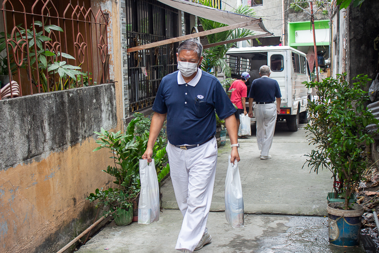 Tzu Chi volunteer Loreto Balete carries bags of groceries to the blind beneficiaries.  【Photo by Marella Saldonido】