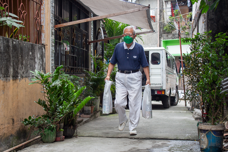 Tzu Chi volunteer Ati Chong carries bags of groceries to the blind beneficiaries.  【Photo by Marella Saldonido】