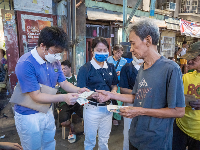 A beneficiary accepts a ₱500 Puregold gift certificate from a member of Tzu Chi Youth. 【Photo by Matt Serrano】