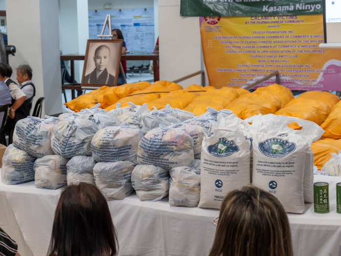 Sacks of 10-kg rice and coin banks from Tzu Chi are lined up next to other relief goods claimed by the 189 families affected by the April 16 blaze in Barangay Batis, San Juan. Beneficiaries also received cash assistance from the San Juan City local government and the Department of Social Welfare and Development (DSWD), and goods from DSWD and the Federation of Filipino-Chinese Chambers of Commerce and Industry Foundation Inc. 【Photo by Marella Saldonido】