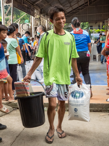 Beneficiaries are all smiles as they leave the distribution area with Tzu Chi’s relief goods. 