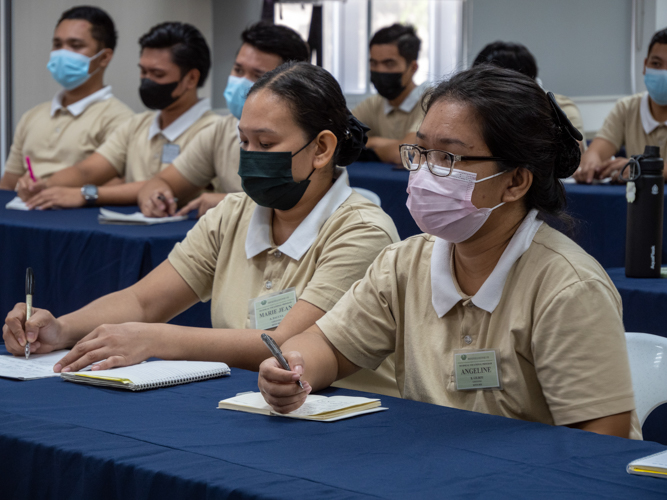 Tech-Voc Caregiving students Mary Jean Dacuya and Angeline Gilboy jot down notes during a keynote speech. 【Photo by Matt Serrano】