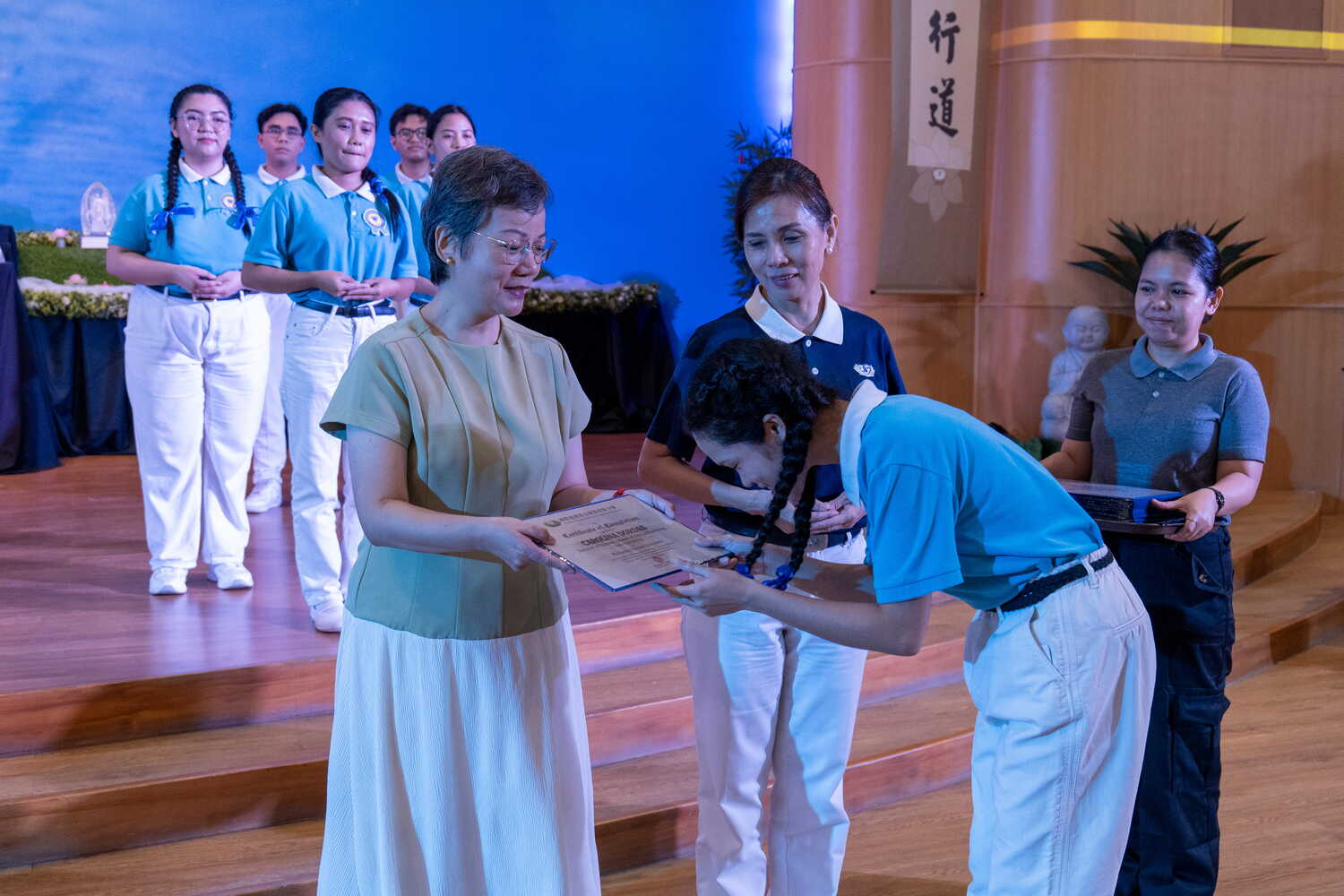 Abigail See of the John and Mary Kaw Charitable Foundation, Inc. (left) joins Tzu Chi Davao Deputy OIC Mei Yuen in presenting graduating scholars with their certificate. 