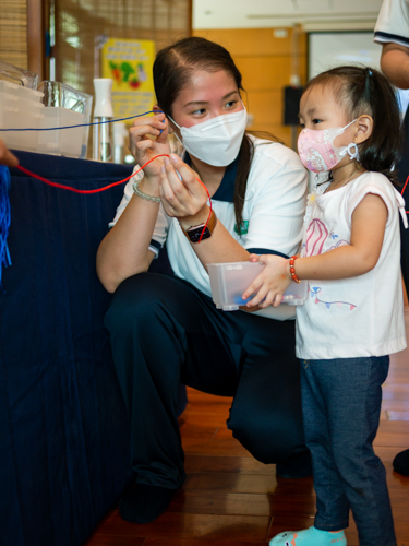 Directress Jane helping a kid with arts and crafts【Photo by Daniel Lazar】