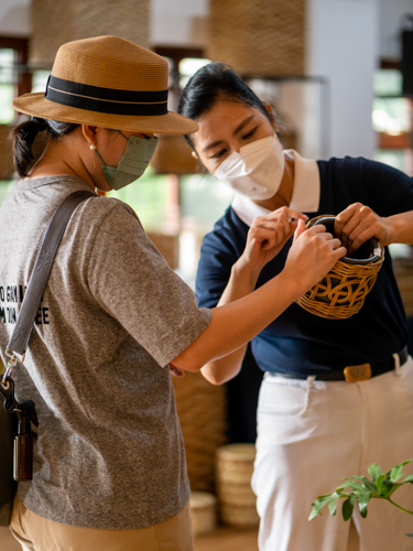 Tzu Chi volunteer Pansy Ho showcasing one of the rattan products to one of the bazaar guests.【Photo by Daniel Lazar】