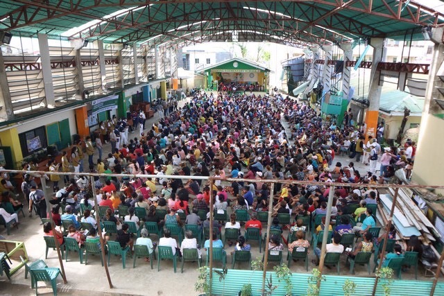 Recipients of Tzu Chi’s aid gather in a covered court. 