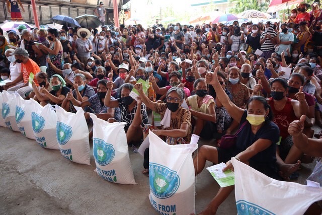 Cebu beneficiaries give their two thumbs up after claiming their 20-kg rice relief. 
