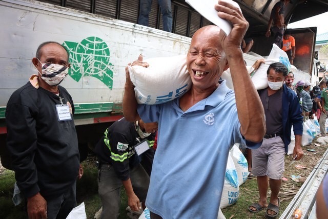 A man cheers in glee after receiving his rice relief. 