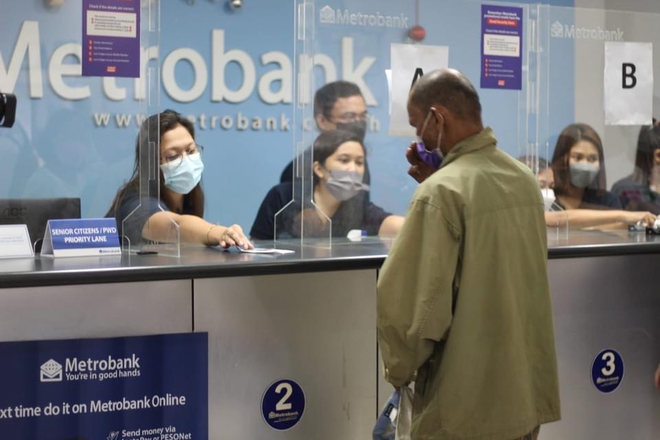 Inside Metrobank Sogod, a teller gives an envelope of cash assistance to a beneficiary. 