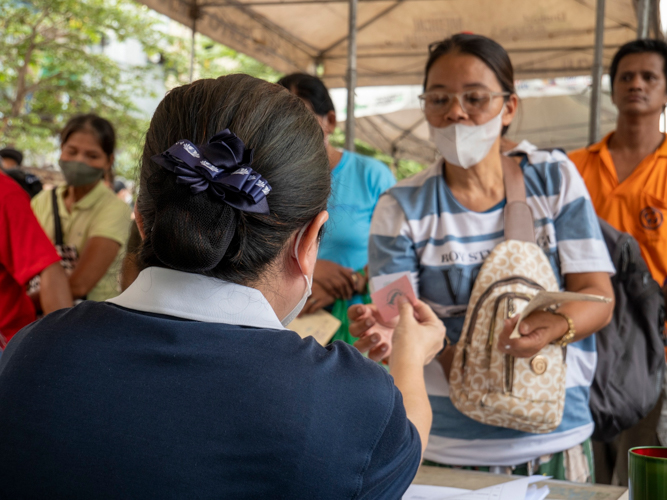 A volunteer hands out a stub to a beneficiary for her to claim relief. 【Photo by Matt Serrano】
