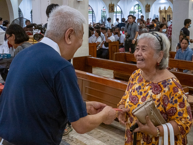 The parishioners receive a red envelope (angpao) blessed by Tzu Chi founder Dharma Master Cheng Yen. 【Photo by Matt Serrano】