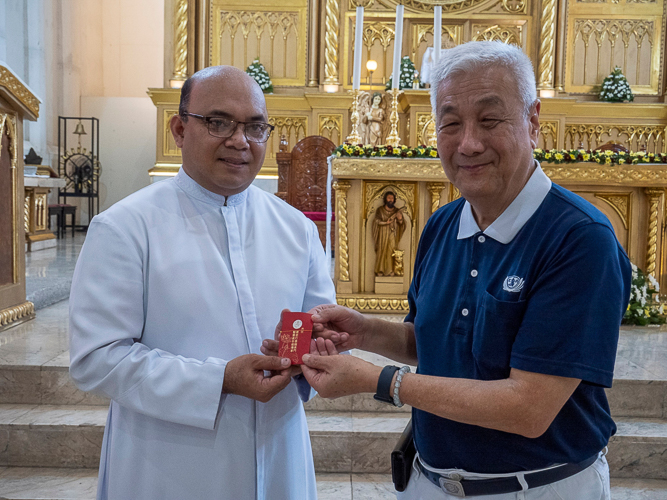 The parishioners receive a red envelope (angpao) blessed by Tzu Chi founder Dharma Master Cheng Yen. 【Photo by Matt Serrano】