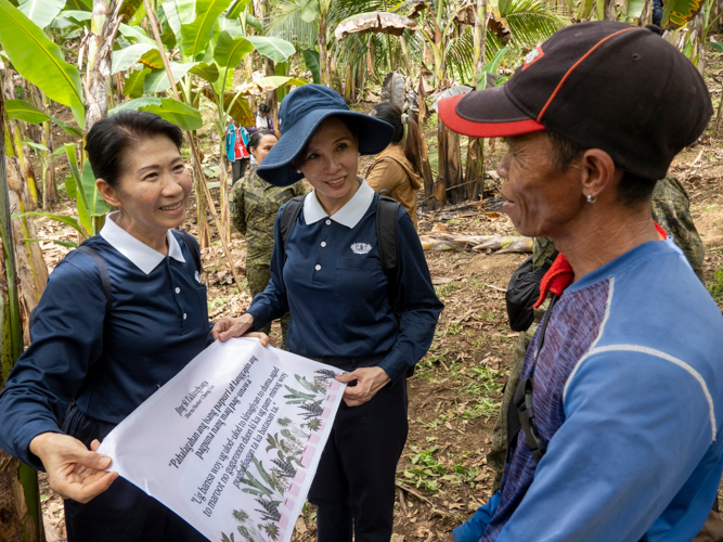 Tzu Chi volunteers Woon Ng and Ang Mei Yuen share a Jing Si Aphorism translated into the local language with a farmer. 【Photo by Matt Serrano】