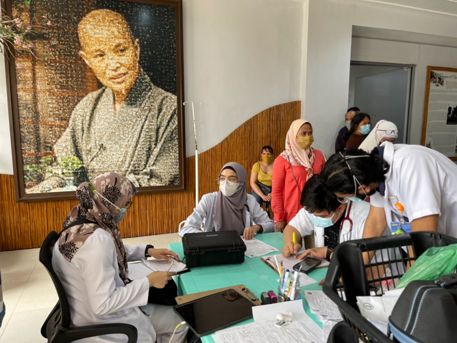 Patients line up for medical treatment at this area of the hall where a mosaic of Master Cheng Yen’s portrait composed of Tzu Chi Zamboanga’s mission photos hangs on a wall. 【Photo by Harold Alzaga】