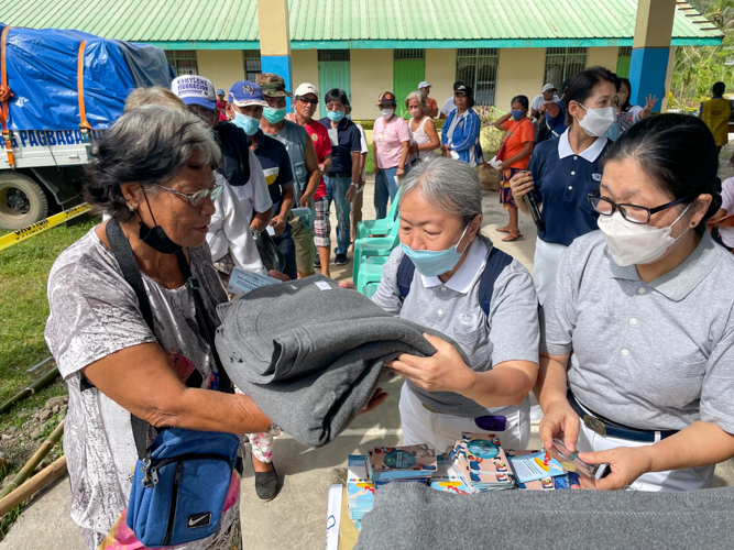 Volunteer hands a blanket over to a beneficiary. 【Photo by Jeaneal Dando】