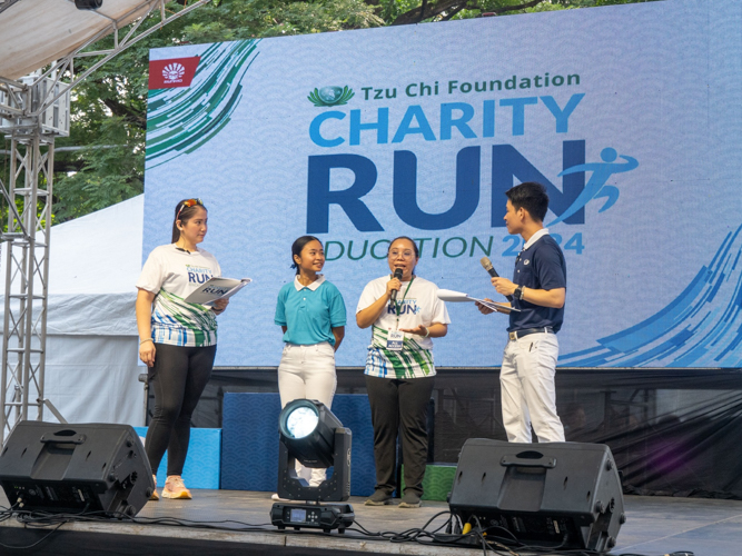 Flanked by Charity Run hosts Jane Sy (first from left) and Spencer Sze (first from right), Tzu Chi scholars Sydney Alipao (second from left) and Cherrie Rose Ang (second from right) explain how a scholarship from the foundation changed their life. 