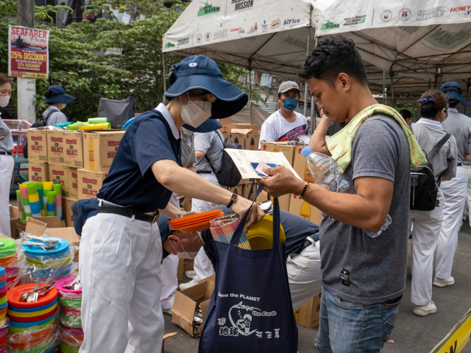 A fire beneficiary receives plates and utensils from a volunteer. 【Photo by Matt Serrano】