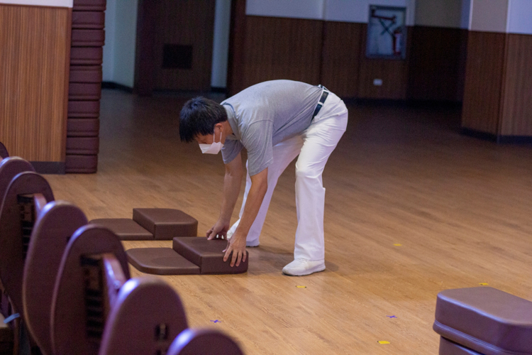 Volunteer Ronald Lee places kneeling pads on the floor of Jing Si Hall while participants are on their break.【Photo by Matt Serrano】