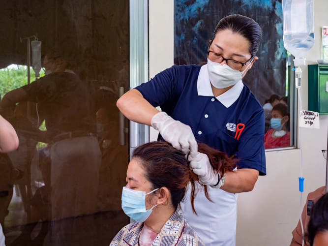 Tzu Chi Zamboanga volunteer Shan Ling Wang looks after a patient and helps tie her hair. 【Photo by Daniel Lazar】