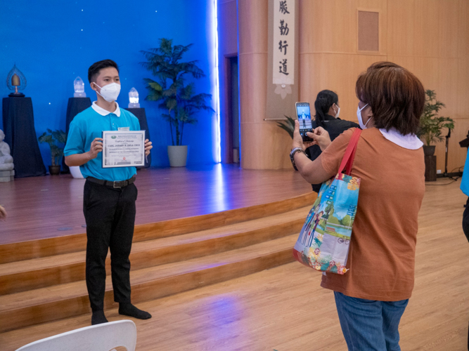 A proud mother snaps a photo of her son holding up his scholarship certificate.【Photo by Matt Serrano】