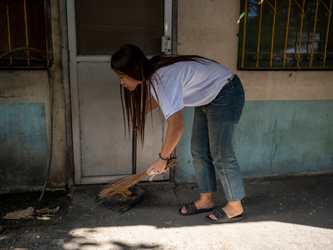 Up early, Gwyenth Co Yu sweeps outside their home in Pandacan, Manila, before preparing coffee for her mother Esther. “I’m very happy because she has improved so much,” says Esther. “Before, you could tell that she wasn’t ‘normal.’ Now you can consider her ‘normal’ even if she’s a little late.”【Photo by Harold Alzaga】