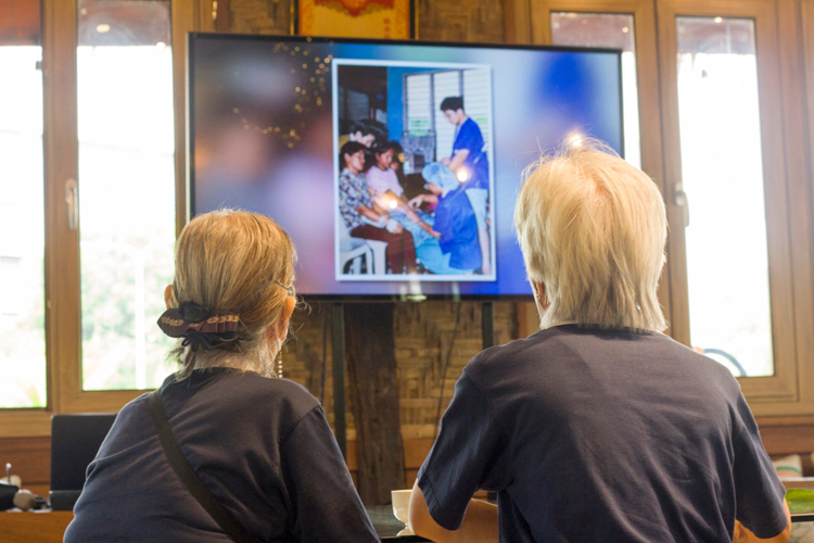 Volunteers relive their years as Tzu Chi volunteers in medical missions through photos flashed on a flat-screen TV. 【Photo by Matt Serrano】