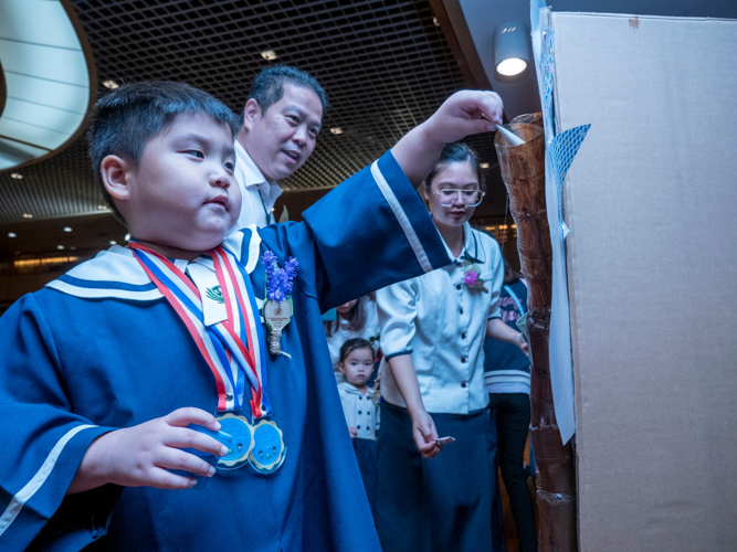 Preschooler Aidan Matteo Ongcarranceja drops his coin can pledges into a collection container as his father Andre looks on. 【Photo by Harold Alzaga】
