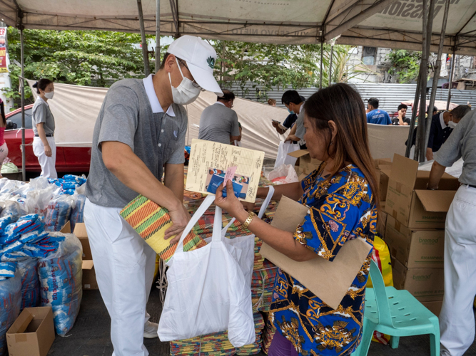 A volunteer places a floor mat in a beneficiary’s eco bag. 【Photo by Matt Serrano】