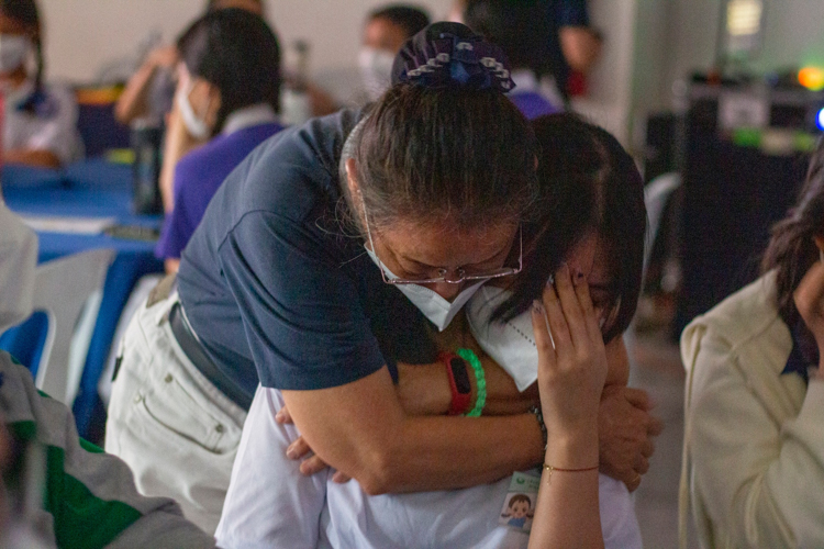 Volunteer comforts a participant with a hug after an emotional session on filial piety. 【Photo by Matt Serrano】
