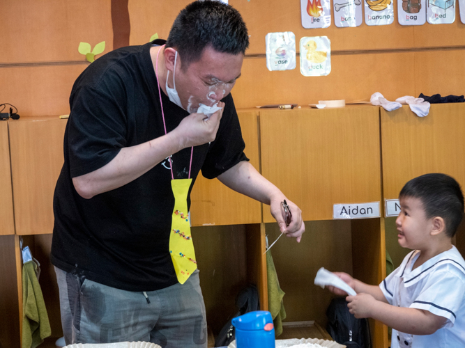 Student gives wet wipes to his father to help him clean after the flour game. 【Photo by Harold Alzaga】