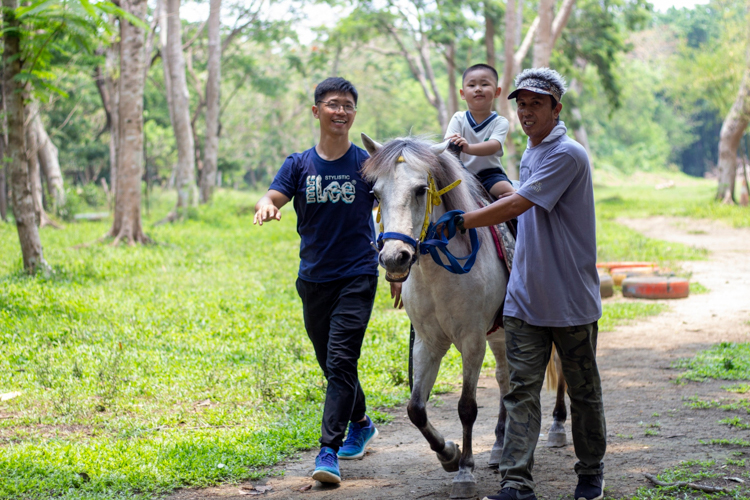 Preschool student Jasper Shi rides a horse with guidance from father Jimmy and a farm personnel. 【Photo by Matt Serrano】