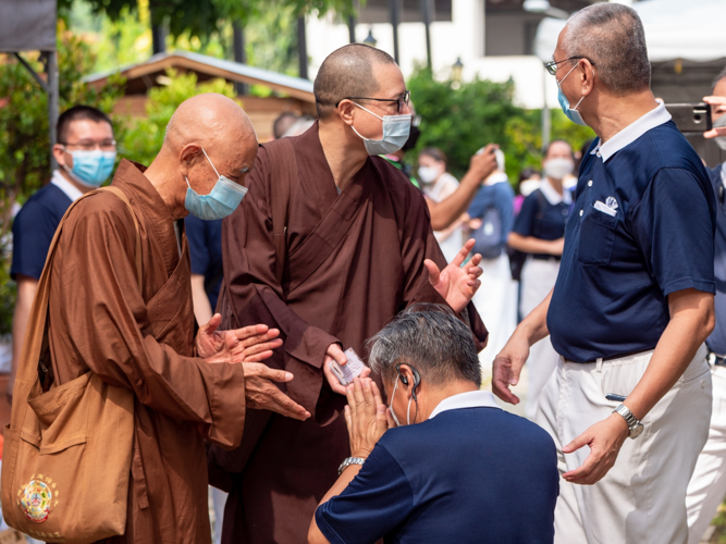 Tzu Chi volunteer Johnny Kwok kneels before Buddhist monks as he gifts them with debit cards used to purchase Fiesta Verde ’22 products. 【Photo by Daniel Lazar】
