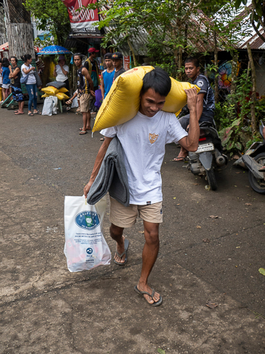 Jonathan Demakiling carries his 25 kilograms of rice, grocery items, and Tzu Chi blanket on his way home. 【Photo by Matt Serrano】