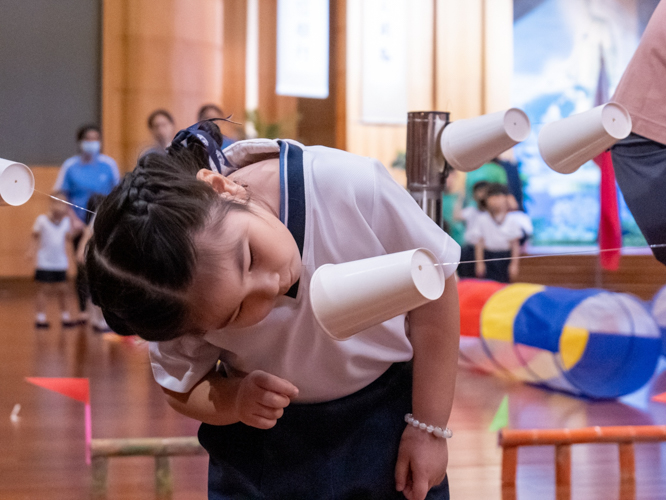In this segment of the obstacle course, students must propel a plastic cup through a nylon string without using their hands. 【Photo by Marella Saldonido】