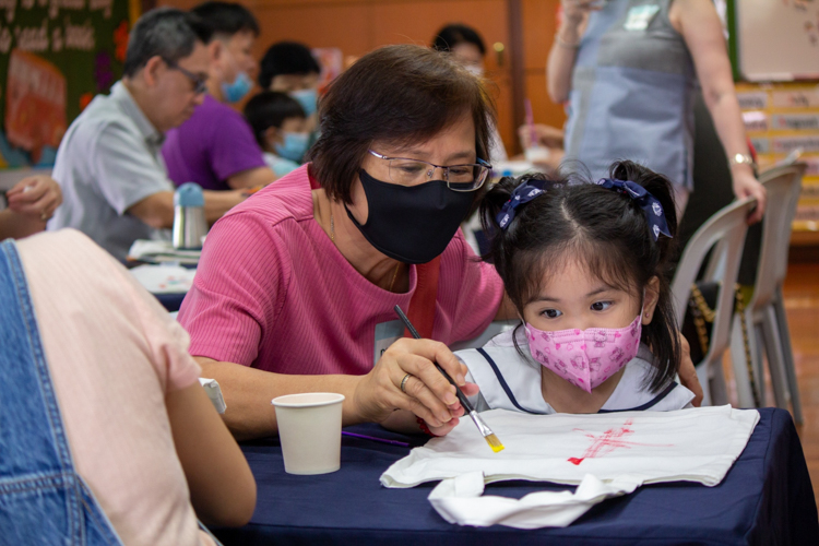 A grandmother guides her granddaughter as she designs a tote bag in a painting session. 【Photo by Marella Saldonido】