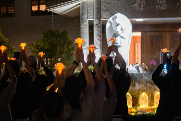 The ceremony concludes as attendees lift their lotus candles while singing a prayer for peace in the world.