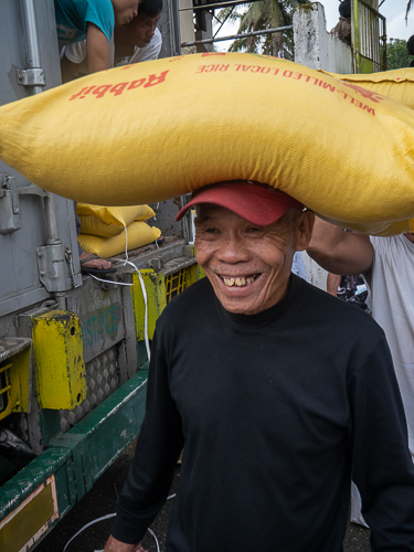 A beneficiary expresses joy as he receives his 25-kilogram sack of rice. 【Photo by Matt Serrano】