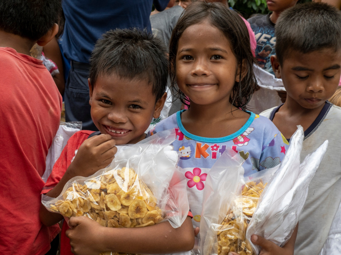The joy is evident on the faces of farmers' children as they happily receive banana chips and other gifts from Tzu Chi volunteers. 【Photo by Matt Serrano】